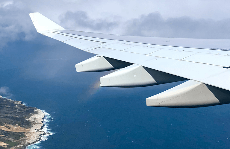 Airplane wing flying over ocean