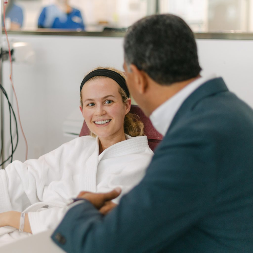 Dr. Tony Jimenez speaking with a smiling patient at Hope4Cancer