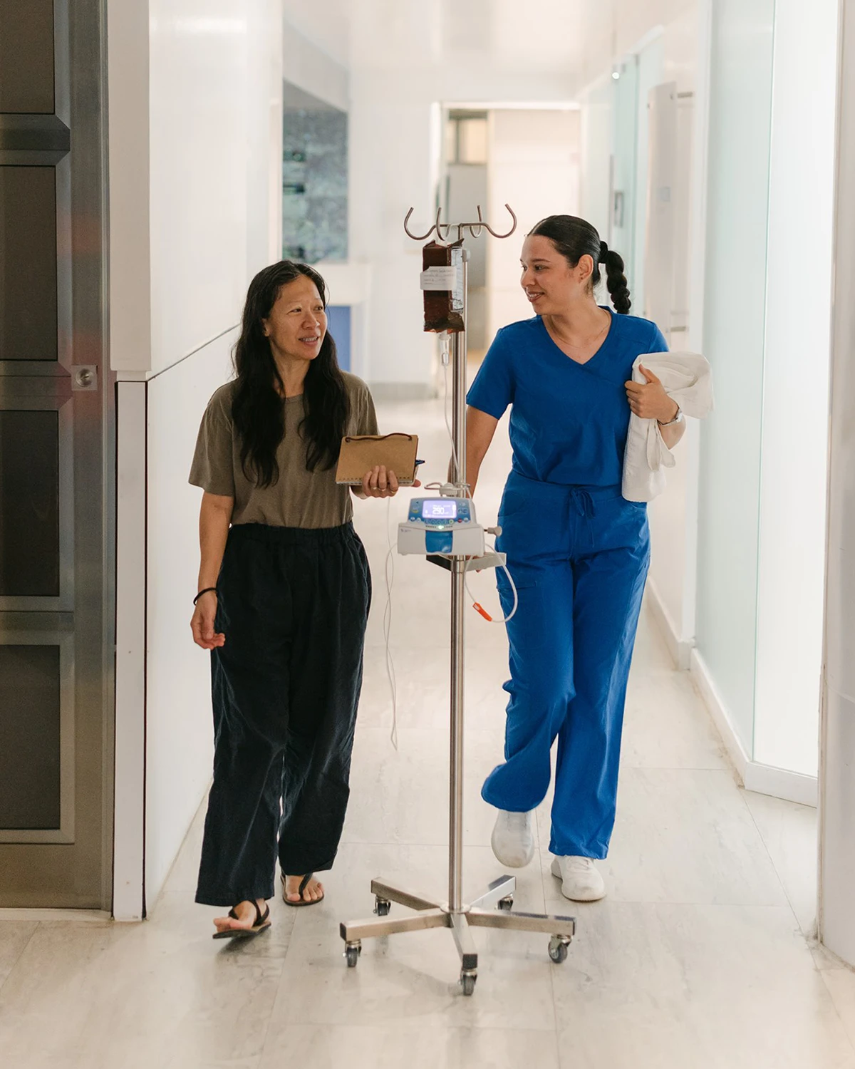 A nurse and a patient walking down a hallway